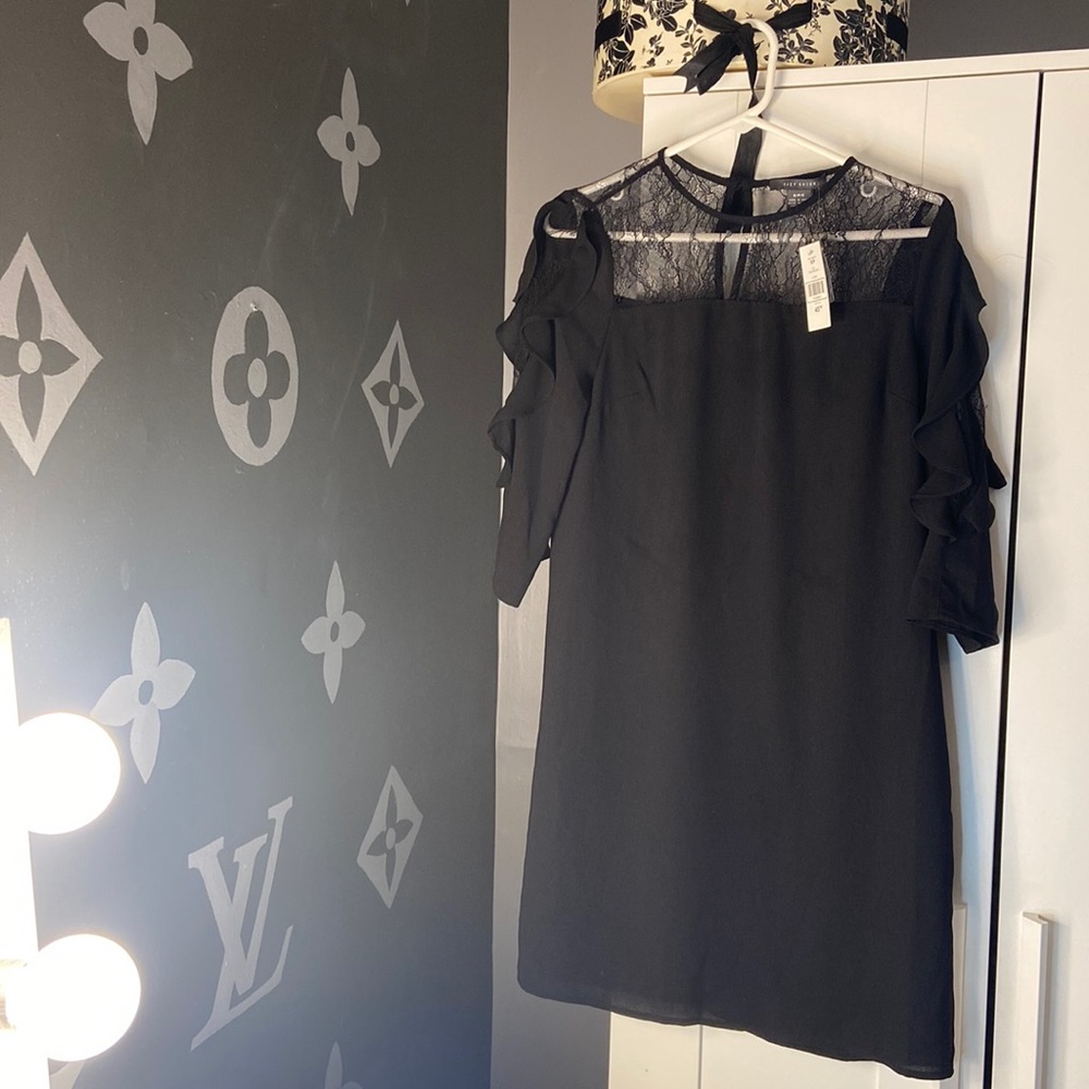A pretty black dress with accent trim around the neck and down the arms.